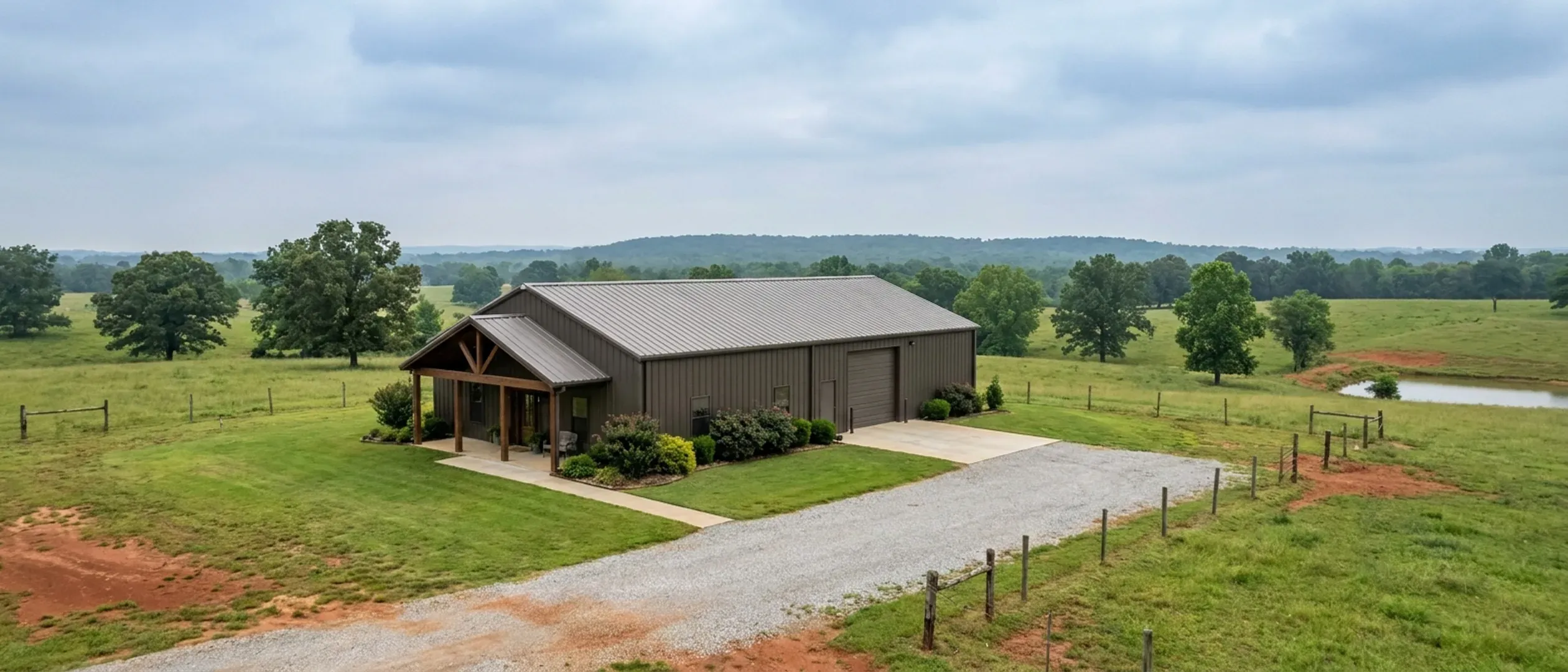 A completed barndominium with a covered entry porch and an attached shop bay, photographed in flat overcast daylight.